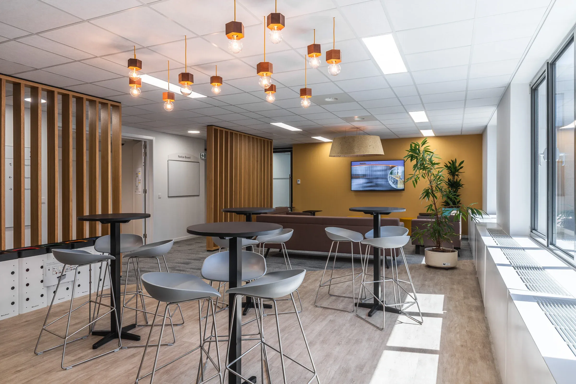 Espace collaboratif avec assises variées et luminaires suspendus