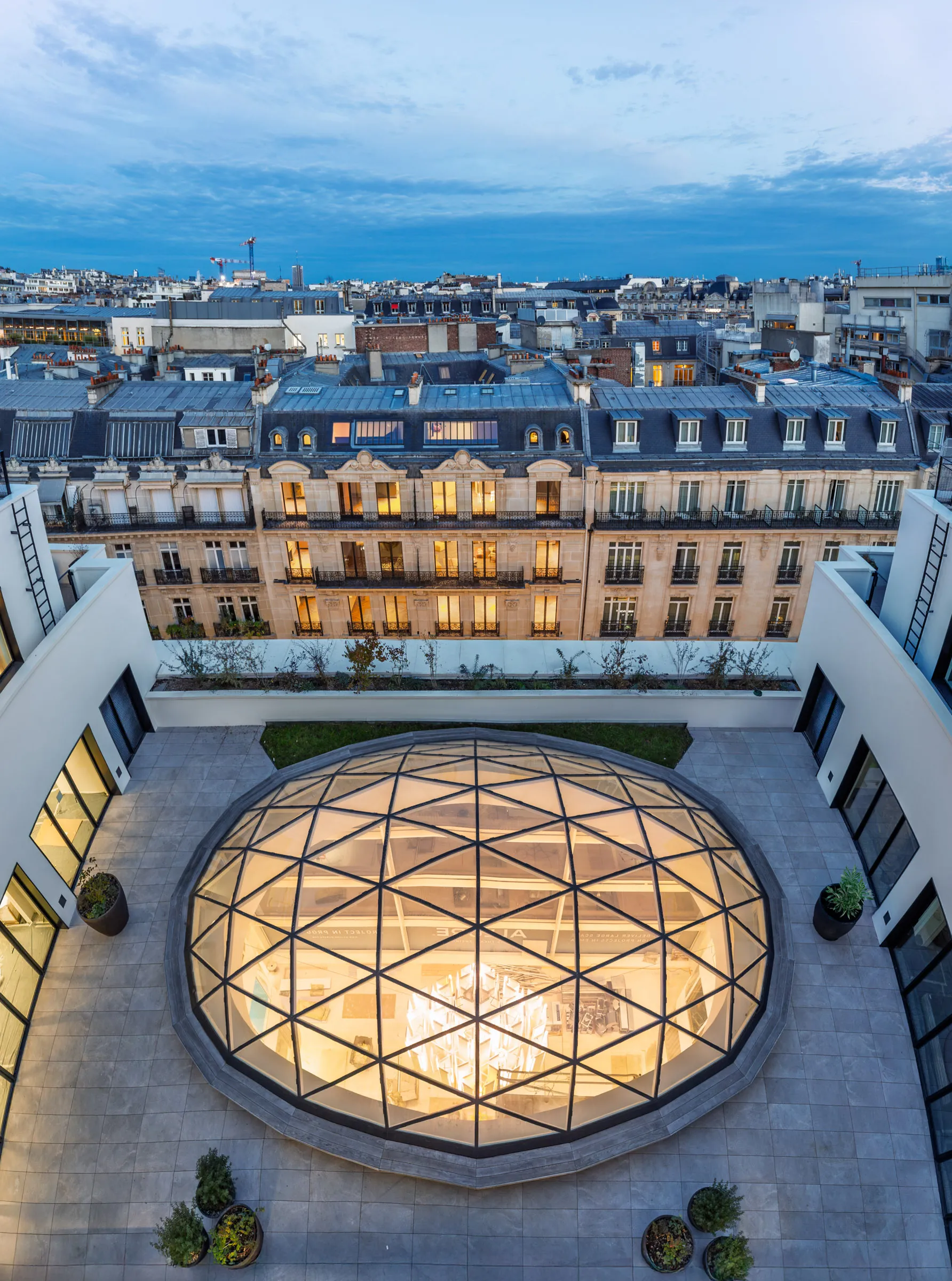 Terrasse en toiture et verrière facettée ouvrant l’atrium sur les toits de Paris