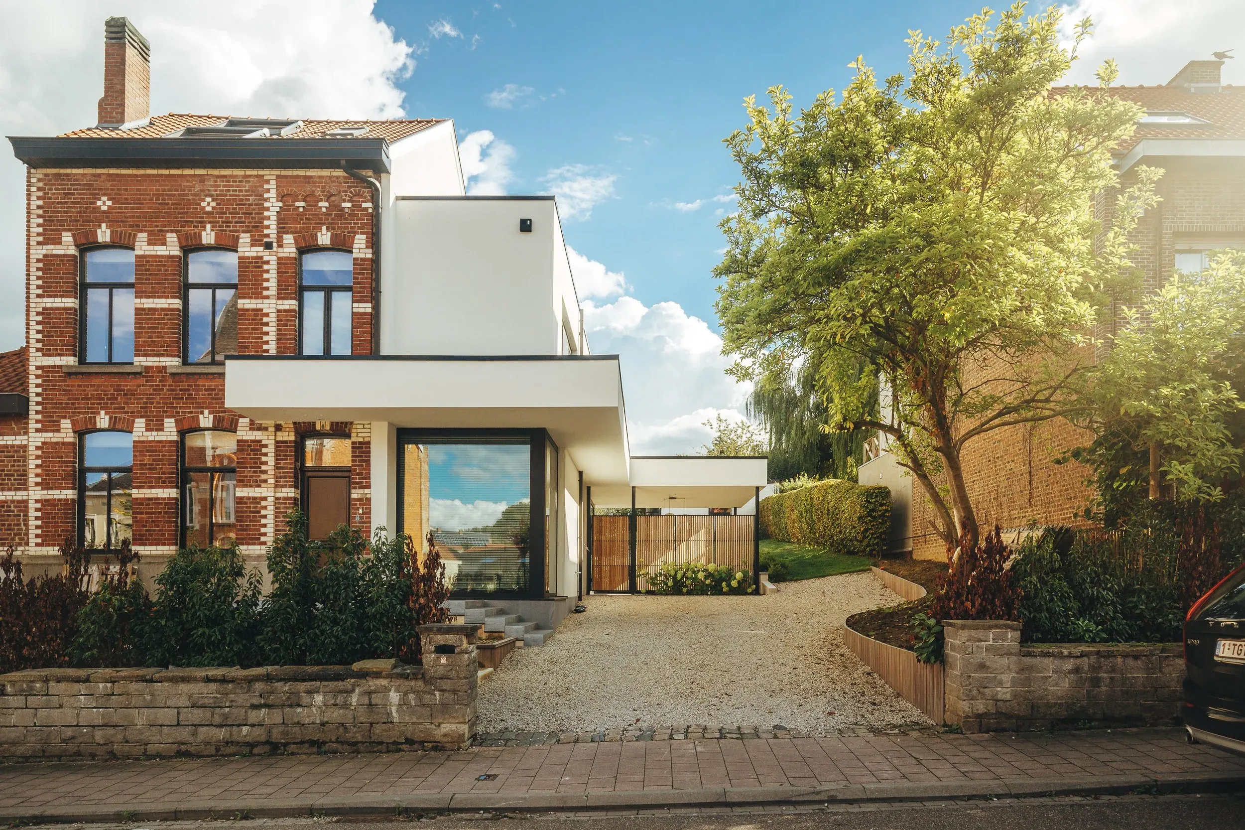 Maison en brique et extension blanche vues depuis la pelouse