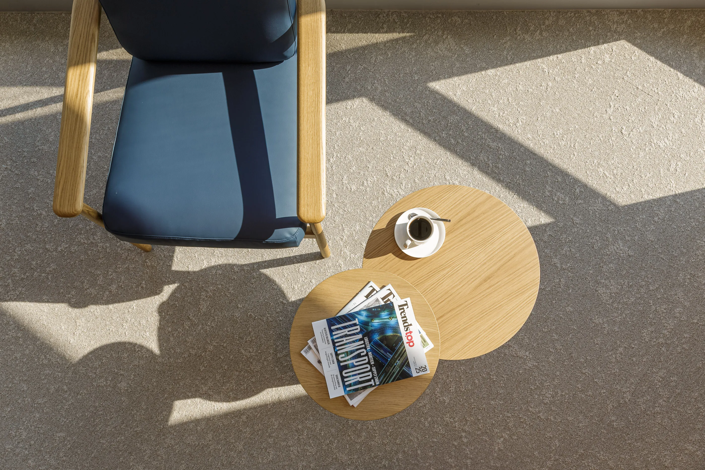 Lumière et ombres des fenêtres sur un fauteuil bleu et des tables en bois superposées