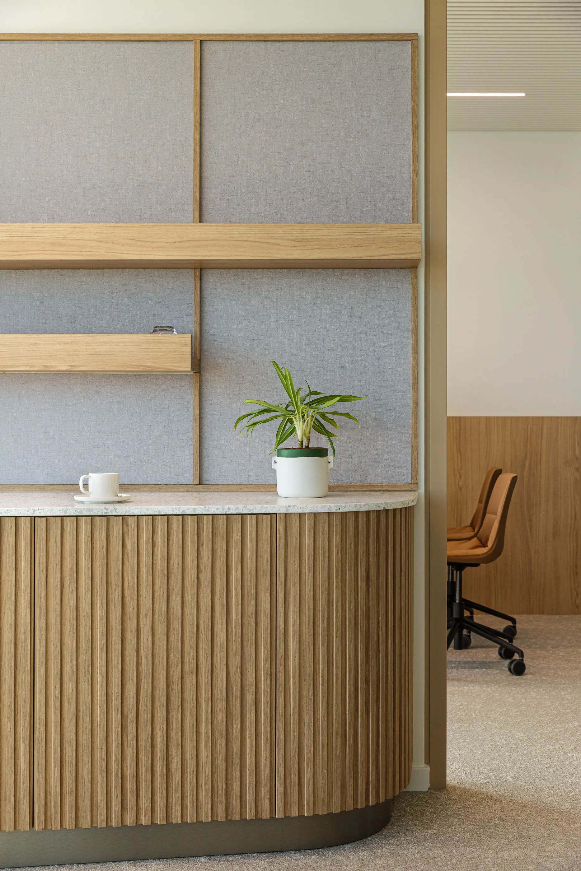 Comptoir cannelé en bois avec une plante en pot, à côté d’une salle de réunion ouverte