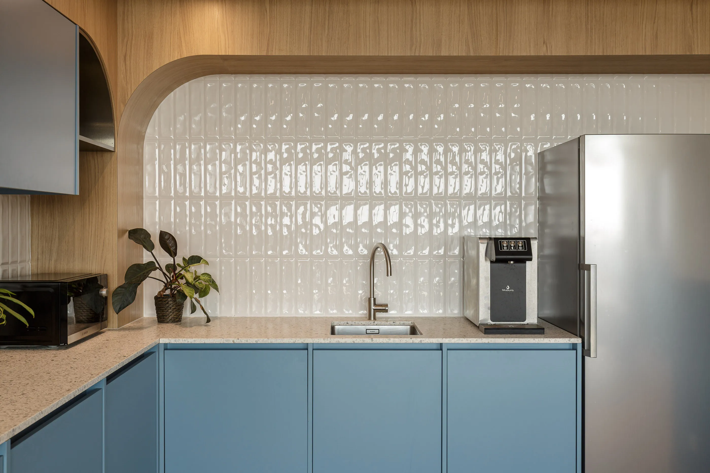 Kitchenette bleue avec crédence en carreaux blancs brillants et appareils en acier inoxydable