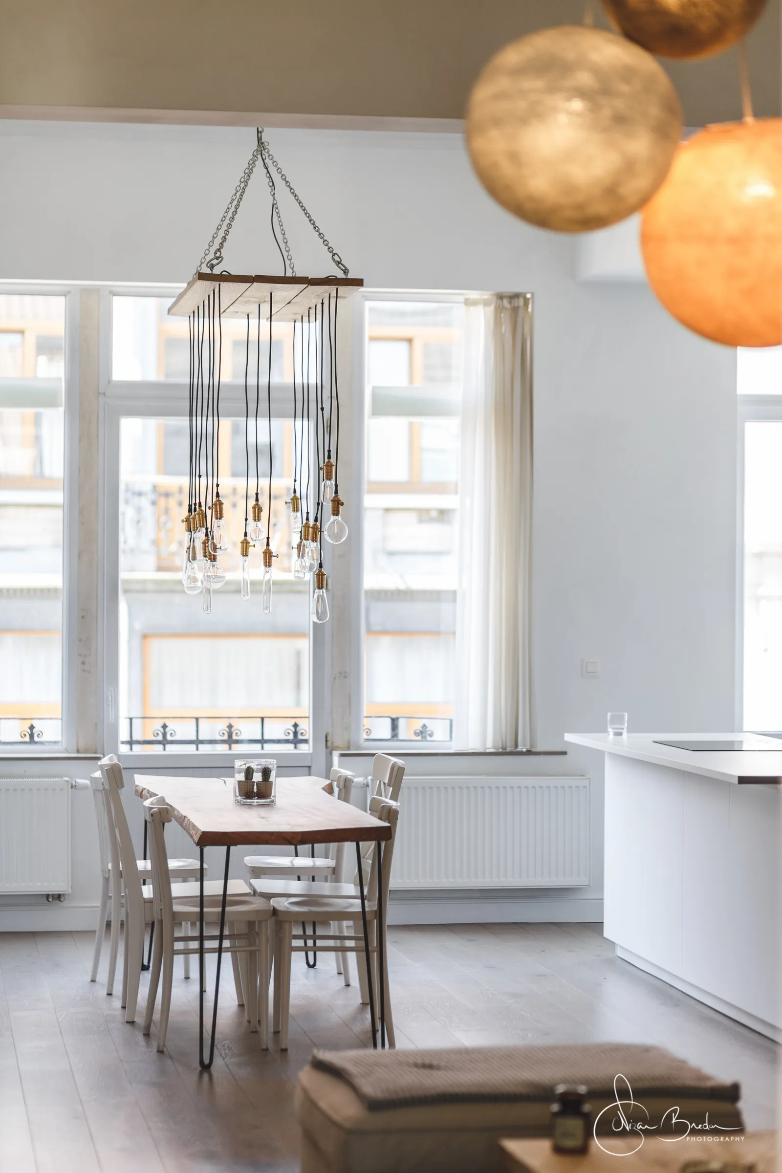 White kitchen opening across the timber dining table towards the living room
