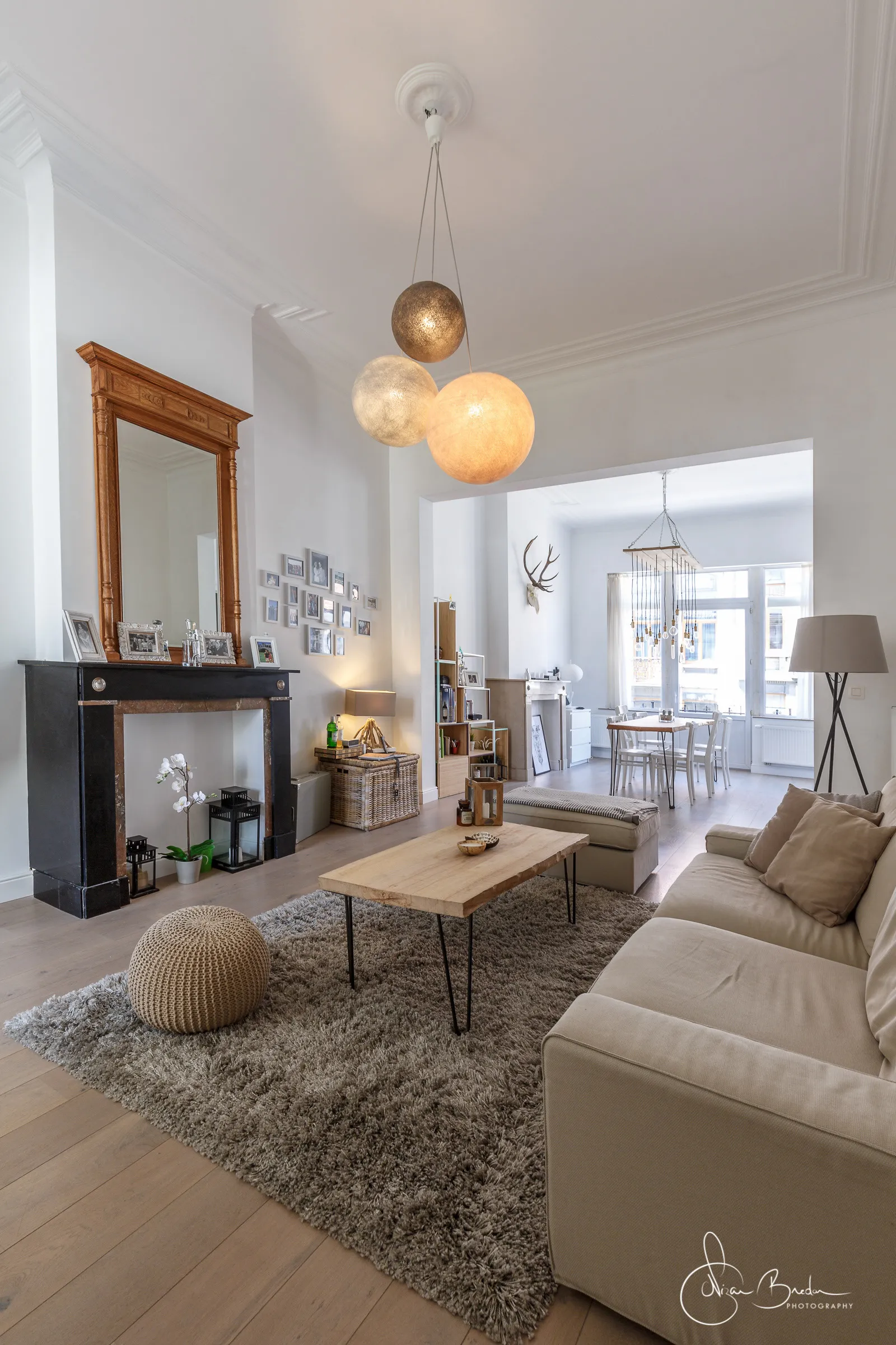 Living room opening towards the dining room beneath three spherical pendant lights