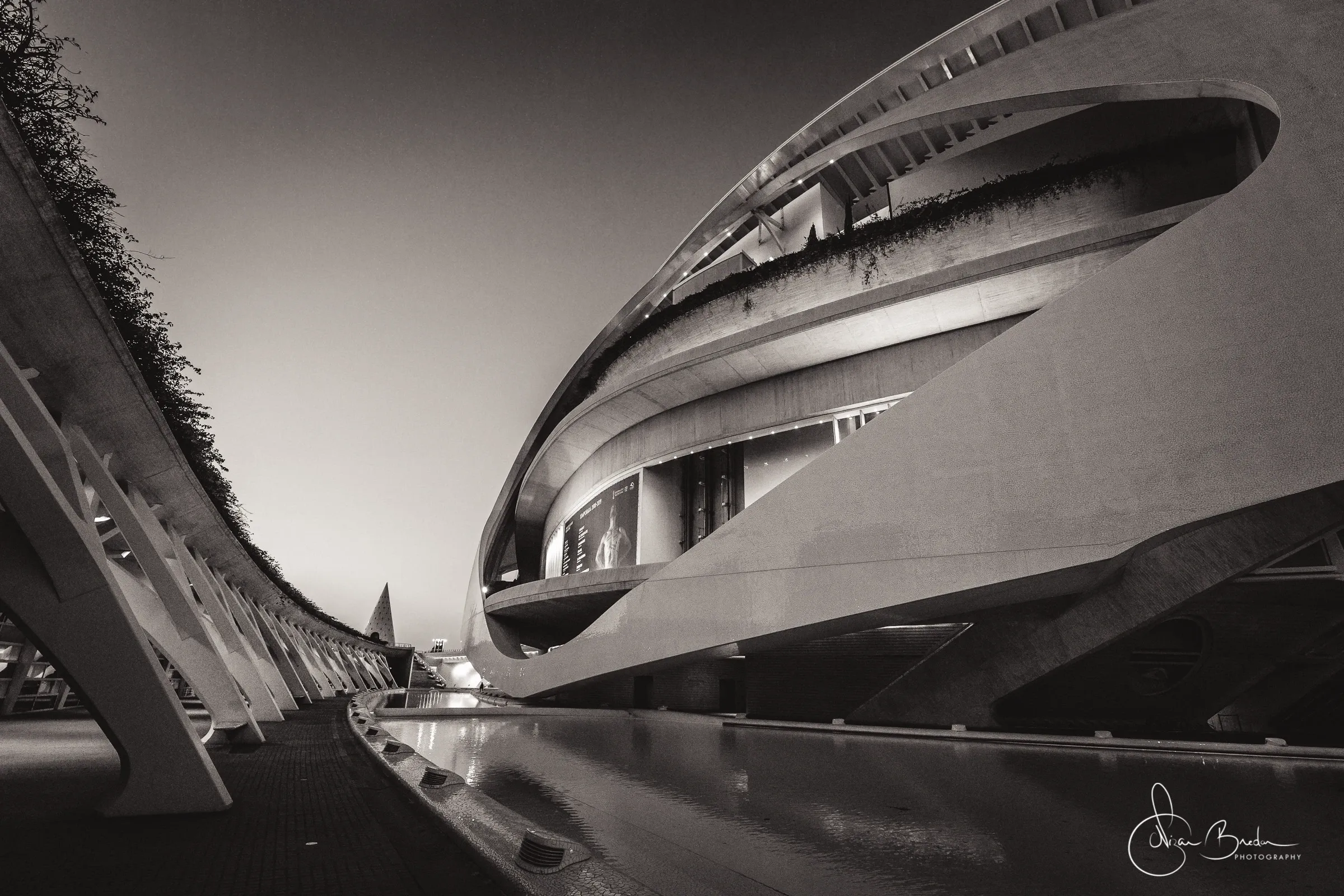 Curved white facade and its dark reflection across the water