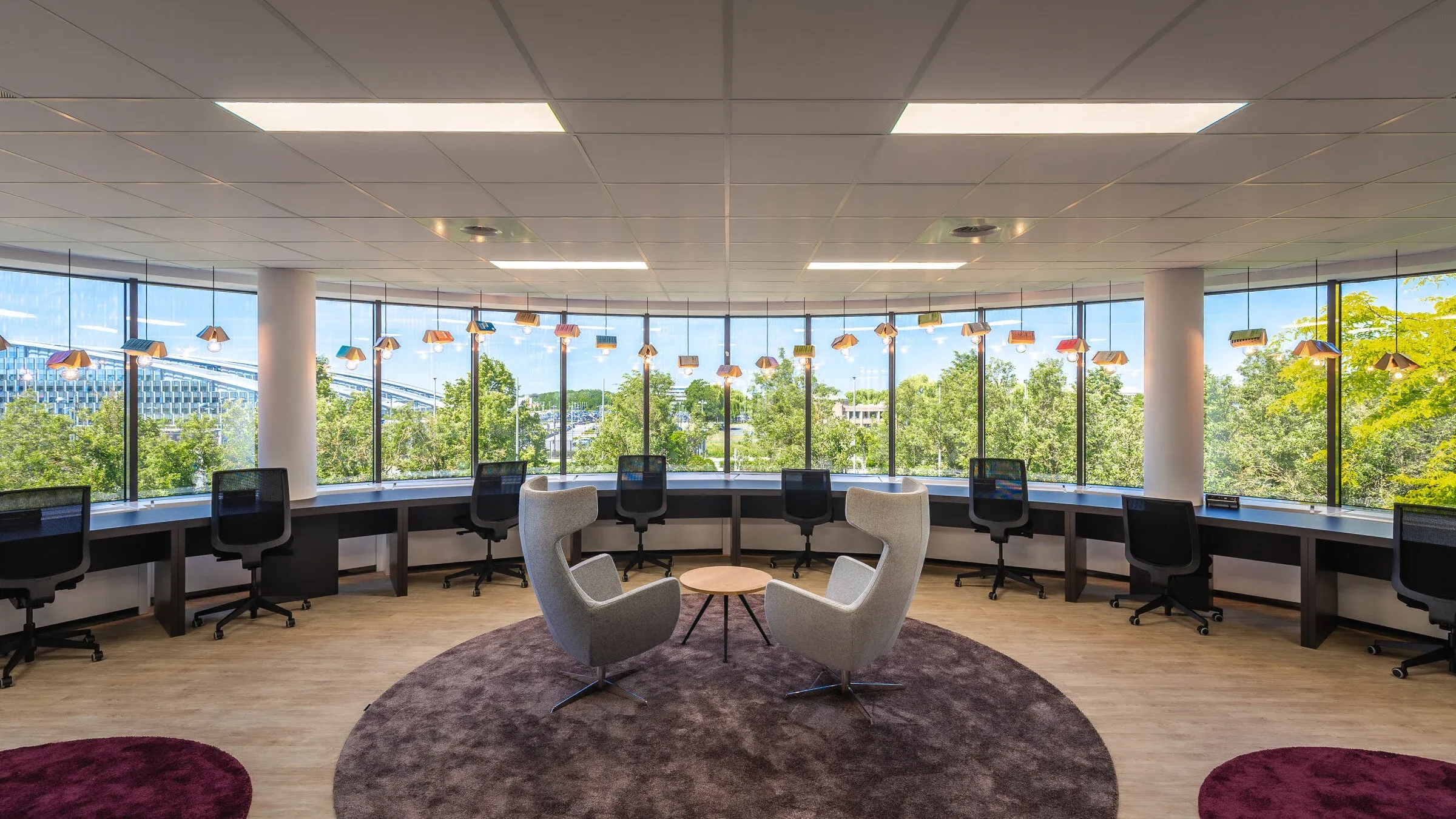 Espace de travail ouvert devant des fenêtres panoramiques et des luminaires en forme de livres