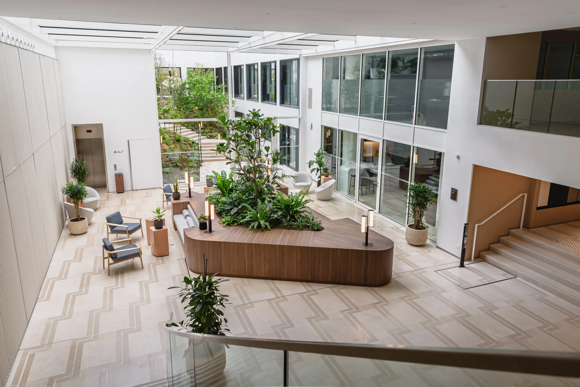 Salon intérieur planté composé autour d’assises souples, de sols en pierre et d’une table centrale sculptée